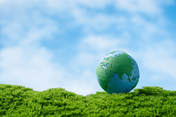 ESG and earth day concept. Globe on fresh green moss blue sky background, environmental protection, sustainability, climate action, and global eco responsibility for sustainable development goals.