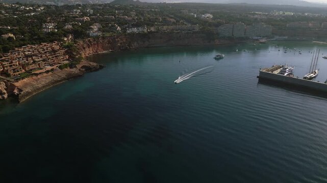 Vista a&eacute;rea de Puerto Adriano en Mallorca con lancha motora pasando por debajo.