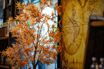 Decorative interior tree with golden leaves standing near an old map