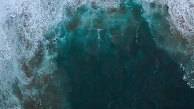 Aerial view of turquoise ocean waves crashing onto the shore, creating a mesmerizing display of power and beauty, Algarve, Faro District, Portugal.