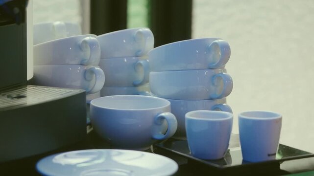 Blue ceramic cups stacked on tray next to coffee machine indoors