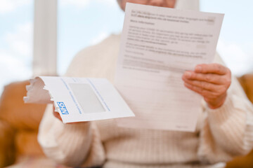 Elderly person reading important letter at home during daytime