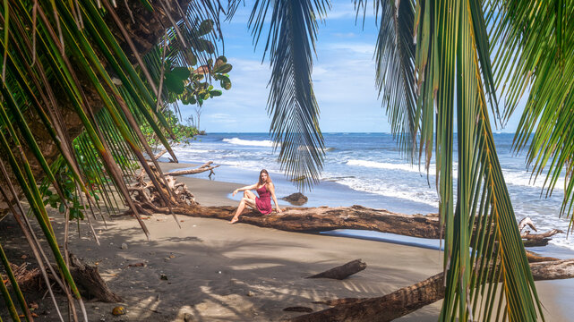 Girl with long hair posing in purple mini skirt on the caribbean beach Playa Puerto Vargas with palm trees in Cahuita National Park in Costa Rica