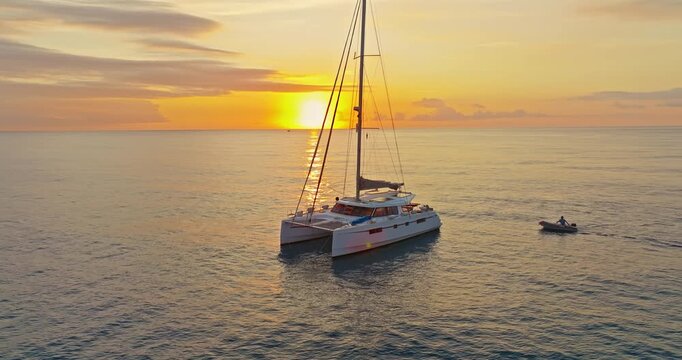 Aerial view of catamaran anchored in the calm sea at amazing sunset