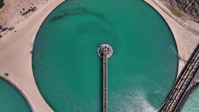 Aerial view of turquoise circular pools surrounded by pale sandy earth and industrial structures, creating a stark contrast, Arizona, United States.