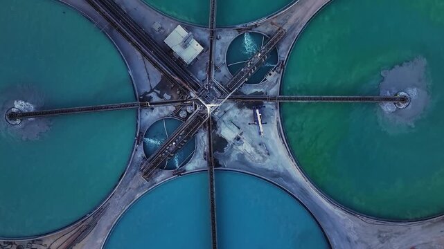 Aerial view of circular water treatment plant pools displaying contrasting colors and textures from a high vantage point, Arizona, United States.
