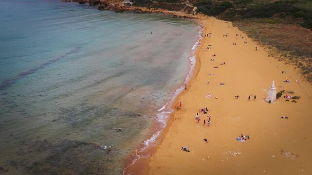 Aerial view of Ramla Bay reveals the golden sands meeting the turquoise waters, people enjoying the beach, Victoria, Malta.