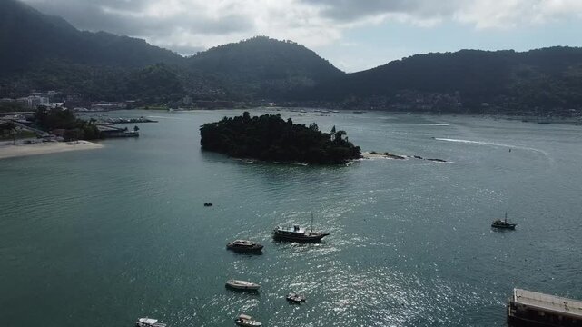 Aerial footage of the Bay Baia da Ilha grande, with the Island Ilha do Coqueiro, anchored boats as well as the rainforest covered mountains in Angra dos Reis in Brazil. 