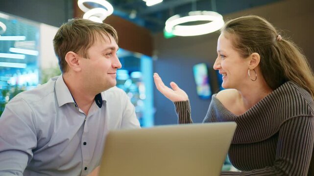 A Focused Conversation Between Two Individuals in a Modern cafe Setting, Engaging with a Laptop and Each Other During Their Meeting