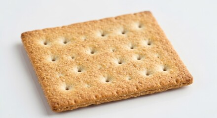Fototapeta premium Close-up shot of a golden-brown, square cracker with tiny holes, resting on a white surface