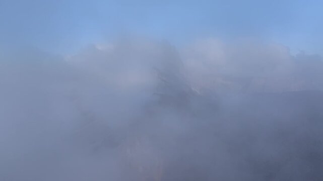 Aerial view of towering mountains shrouded in a dense blanket of fog, creating an ethereal and mysterious atmosphere, Seceda, Trentino-South Tyrol, Italy.