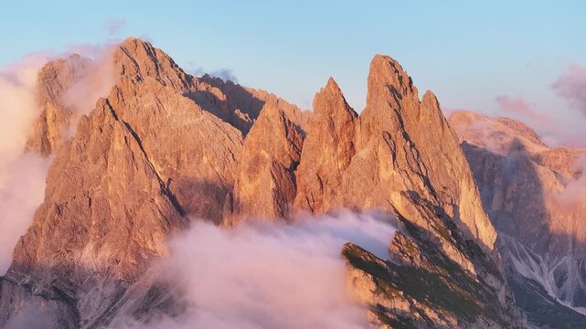 Aerial view of the jagged Seceda mountain peaks piercing through ethereal clouds, showcasing a stunning contrast of textures and tones, Seceda, Trentino-South Tyrol, Italy.
