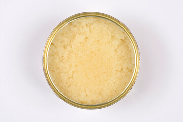 Top down view of an open metal tin can filled with fresh translucent yellow herring roe eggs on a clean white background