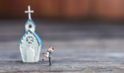 Miniature couple in front of church with space on wood background, valentine background idea, happy marriage couple