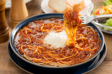 フォークで持ち上げた粉チーズのミートソーススープパスタ