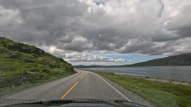 Driving on E6 coastal road in Northern Norway with fjord view and tundra landscape
