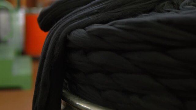 Raw black wool fibers stacked inside a textile factory. Natural material prepared for spinning and textile production in the garment manufacturing process.