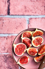 Close-up of bright, fresh, ripe figs on plate, pink stone background