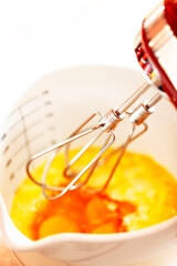 Mixer whisk beats raw eggs into a bowl