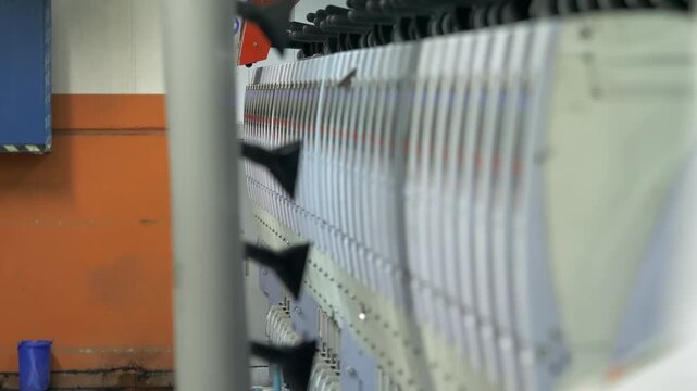 Automated machinery processes wool fibers during textile manufacturing. The industrial machine moves raw material through rollers inside a textile factory production system.