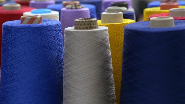 Colorful wool rolls stacked and ready for textile production inside a factory warehouse. The prepared material will be used for fabric manufacturing and garment creation.