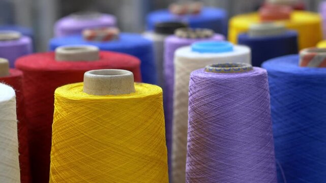 Colorful wool rolls arranged in stacks inside a textile manufacturing facility. The prepared fibers will be used in fabric production and garment industry processes.