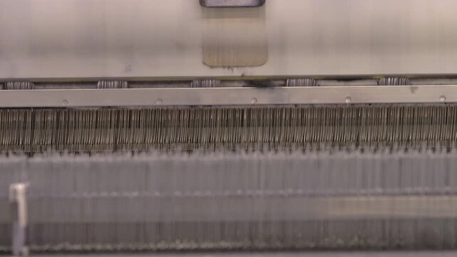 Raw wool fibers move through industrial textile machinery during manufacturing. The factory production process transforms the fibers into textile materials used for fabric production.
