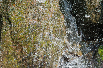 苔むした岩肌に激しく打ち付ける滝の水しぶきと清涼感のある風景