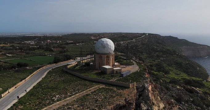Aerial view of the Dingli Radar Station, a geodesic dome perched on a cliff overlooking the sea, with a winding road nearby, Dingli, Dingli Radar, Malta.