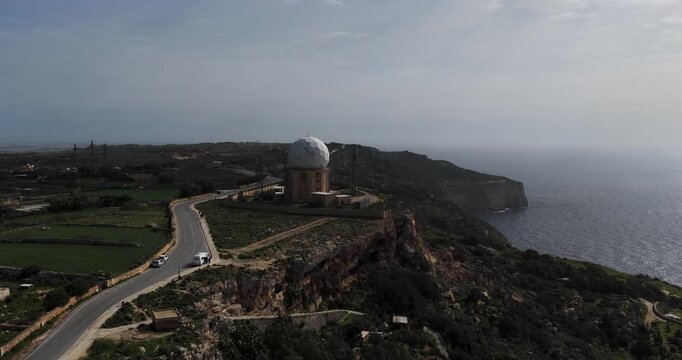 Aerial view of Dingli Radar Station, a white domed structure on a cliff edge, contrasting with the azure sea and the rugged terrain, Dingli, Dingli Radar, Malta.