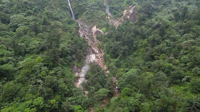 Aerial drone view of the Curug Cikawah waterfall and volcanic crater within Mount Halimun Salak National Park, Indonesia. A pristine tropical landscape and a beautiful ecotourism destination.