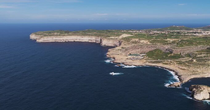 Aerial view of the rugged Dwejra Bay coastline where the azure sea meets the rocky cliffs, creating a stunning contrast of blues and browns, Dwejra Bay, Gozo Island, Malta.
