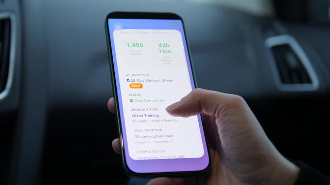 Tracking progress on the go. Person uses a fitness app in the car to view a 30-day workout streak and calories burned. Ideal for modern lifestyle, mobile tech, and sports marketing videos. Sleek