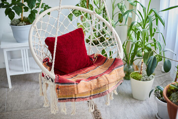 Bright boho interior features wicker hanging chair with natural home decor for relaxed lifestyle