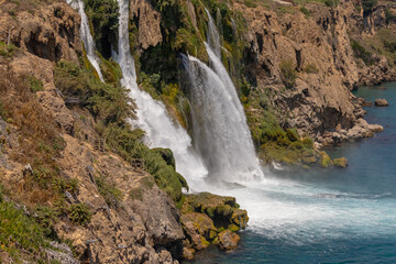 Fototapeta premium The highest freshwater waterfall flowing into the sea. Nizhny Dudensky waterfall in Antalya. Fresh karst water flows into the sea. Bubbling clear water.