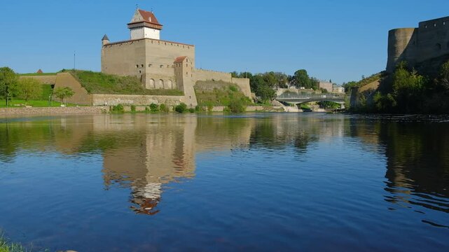 Narva, Estonia &ndash; June 2026: Historic Narva Castle reflected in calm river waters under clear summer sky. Editorial use only.