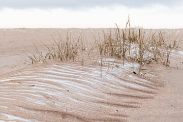 A tranquil winter coastal scene showing snowy sand dunes