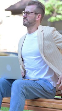 Middle Aged Man Using Laptop with Back Pain while Sitting Outdoor, Vertical Video