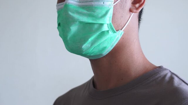 Portrait of man wearing surgical face mask indoors. Male person uses protective accessory during illness and decreased immune system