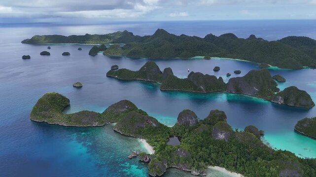 Epic aerial drone view of Wayag, Raja Ampat, Indonesia, showcasing dramatic limestone karst islands surrounded by turquoise lagoons and deep blue ocean. A wide panoramic perspective reveals layered tr