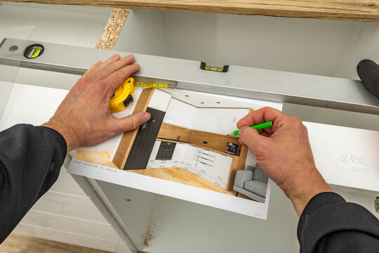 A carpenter makes corrections to a kitchen furniture design, a man draws a kitchen furniture design,