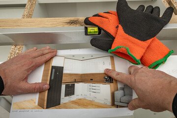 A man wearing carpenter's protective gloves examines a kitchen furniture design, design sketch, protective gloves,