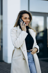 Young woman talking on the phone and walking by the business center