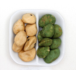 Japanese snacks coated in wasabi powder inside ceramic plate
