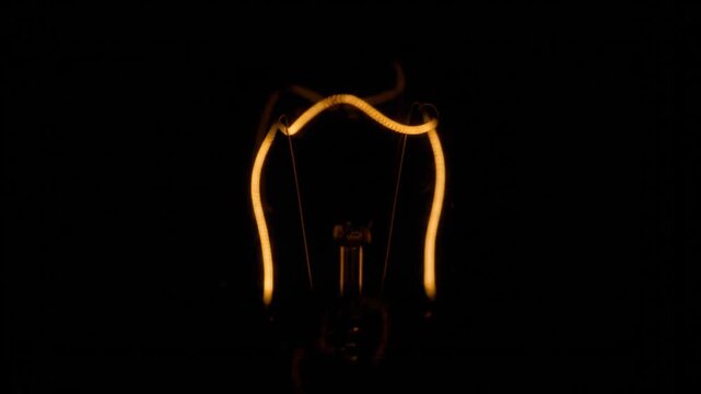 Three incandescent light bulb filaments slowly dim over time, transitioning from brilliant yellow illumination to a faint orange glow and eventually fading completely into the deep black background.