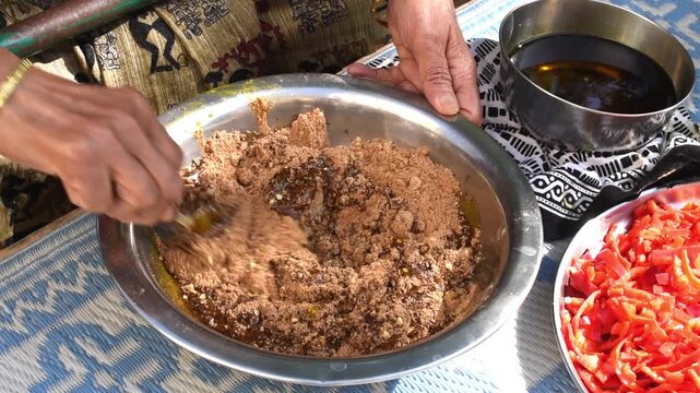 mixing mustard oil in powdered masala for stuffing it in red chilli for achar. 