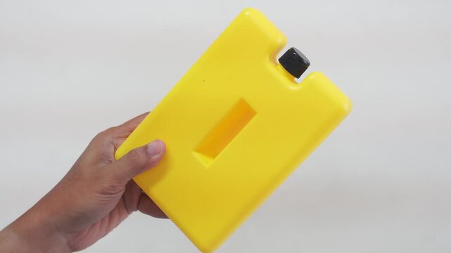 Close-up of male hand holding a yellow ice pack against a swollen red finger. Concept for injury relief, pain treatment, and first aid care in healthcare or sports medicine.