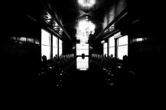 Mesa de madeira, cadeiras, tapete e janelas em sala de reuni&atilde;o. 