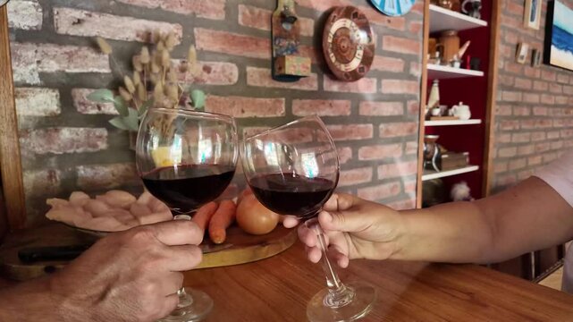 Senior couple toasting with red wine glasses in the kitchen