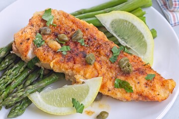 Delicious haddock fish piccata, battered fish fillet with capers, lemon and asparagus, horizontal